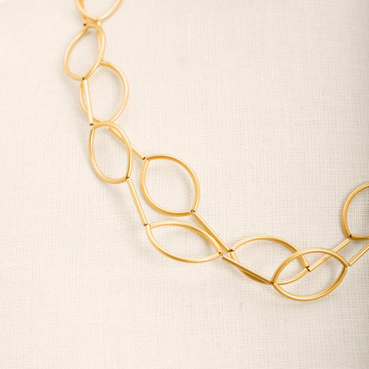 Collana Aurora Oro in tubini di ottone dorato satinato, dettaglio ravvicinato su fondo chiaro
