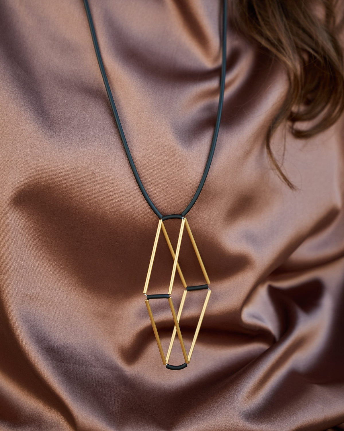 Collana Teorema Oro in ottone dorato e caucciù, variante nero, indossata, dettaglio ravvicinato