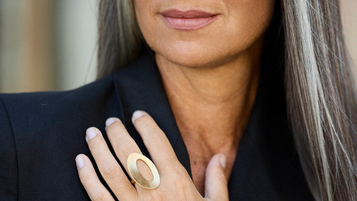 Donna con l'anello Sidney Oval in argento 925 oro satinato, la mano sul petto