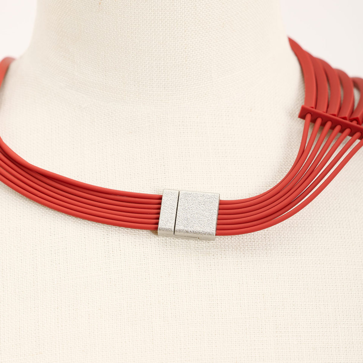 Afrika+ necklace in pastel red on a bust, detail of the clasp