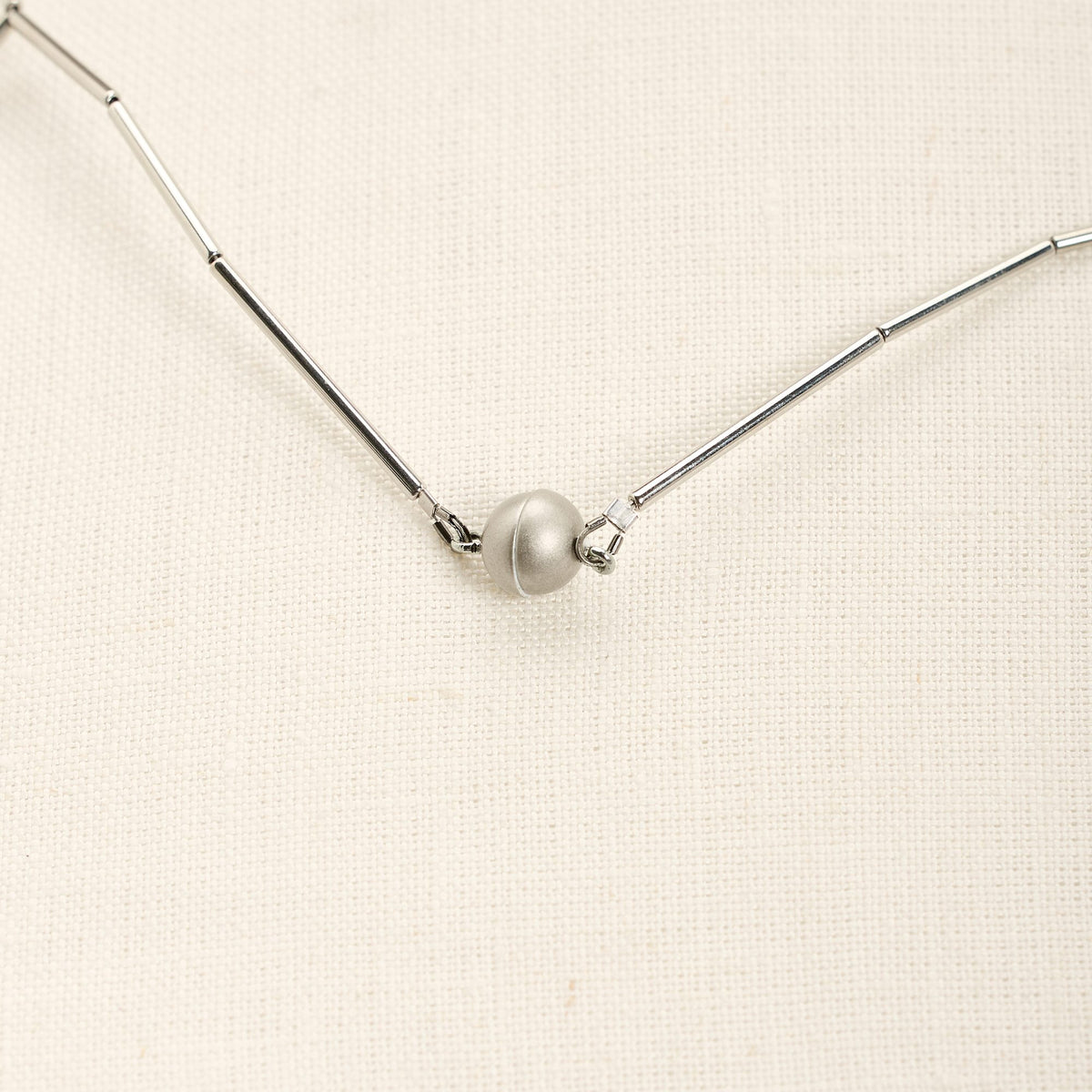Collana Fenice Lunga Rodio in ottone rodiato e sfere in acciaio, su fondo chiaro